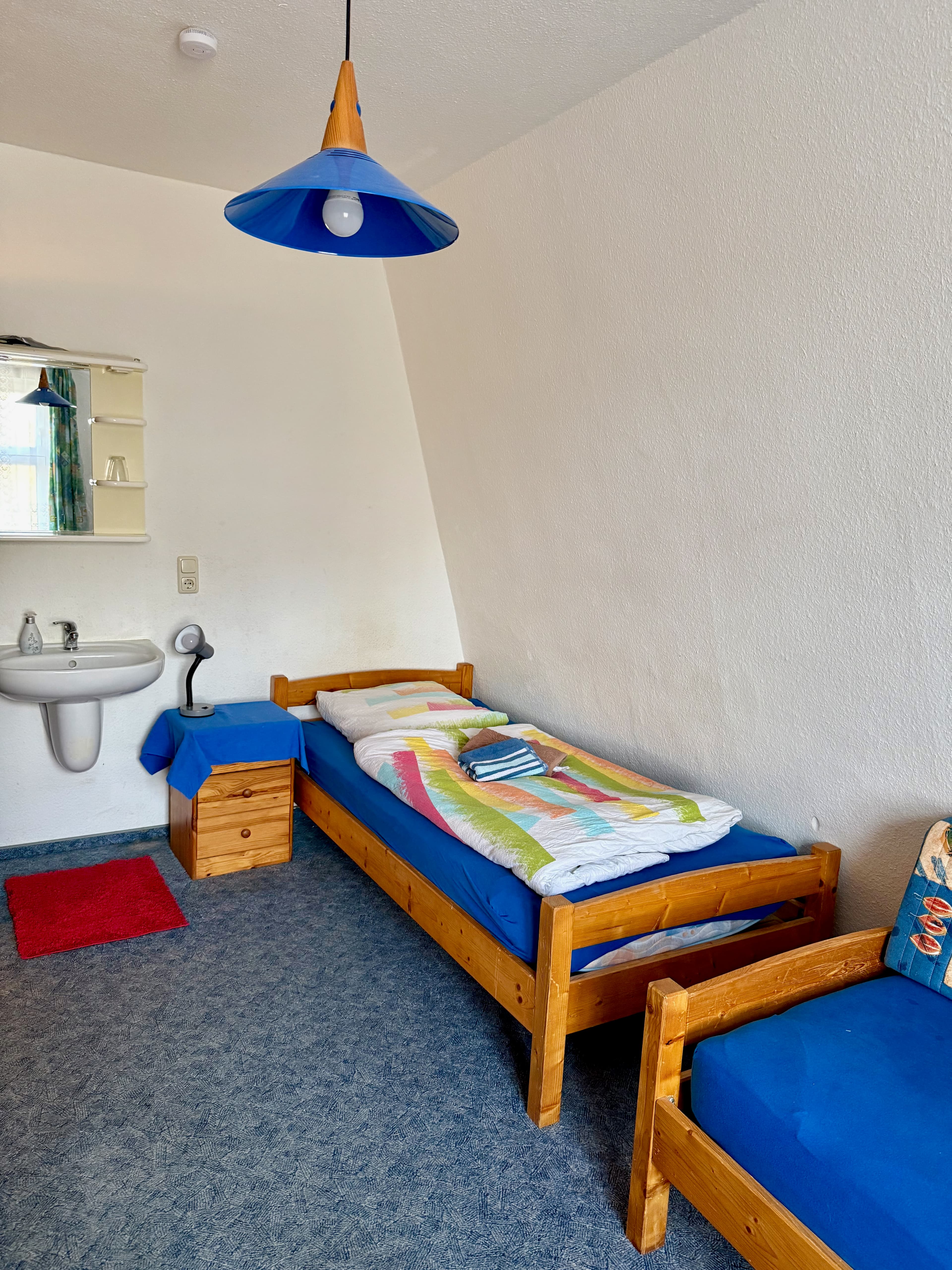 Zimmer mit Einzelbett und Waschbecken im Raum