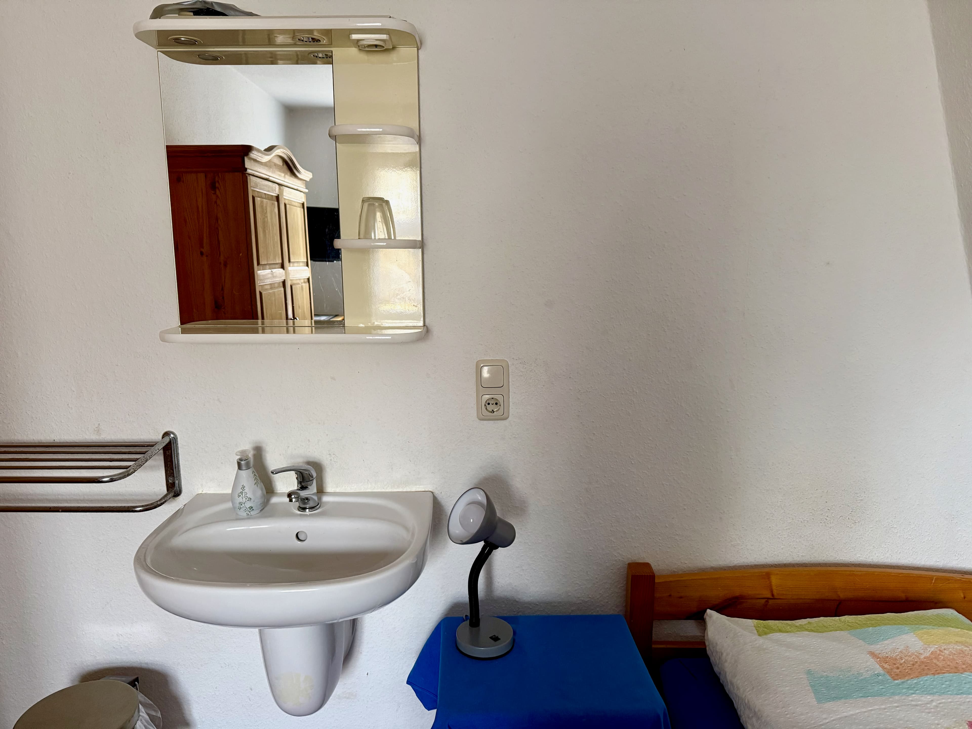 Zimmer mit Einzelbett und Waschbecken im Raum