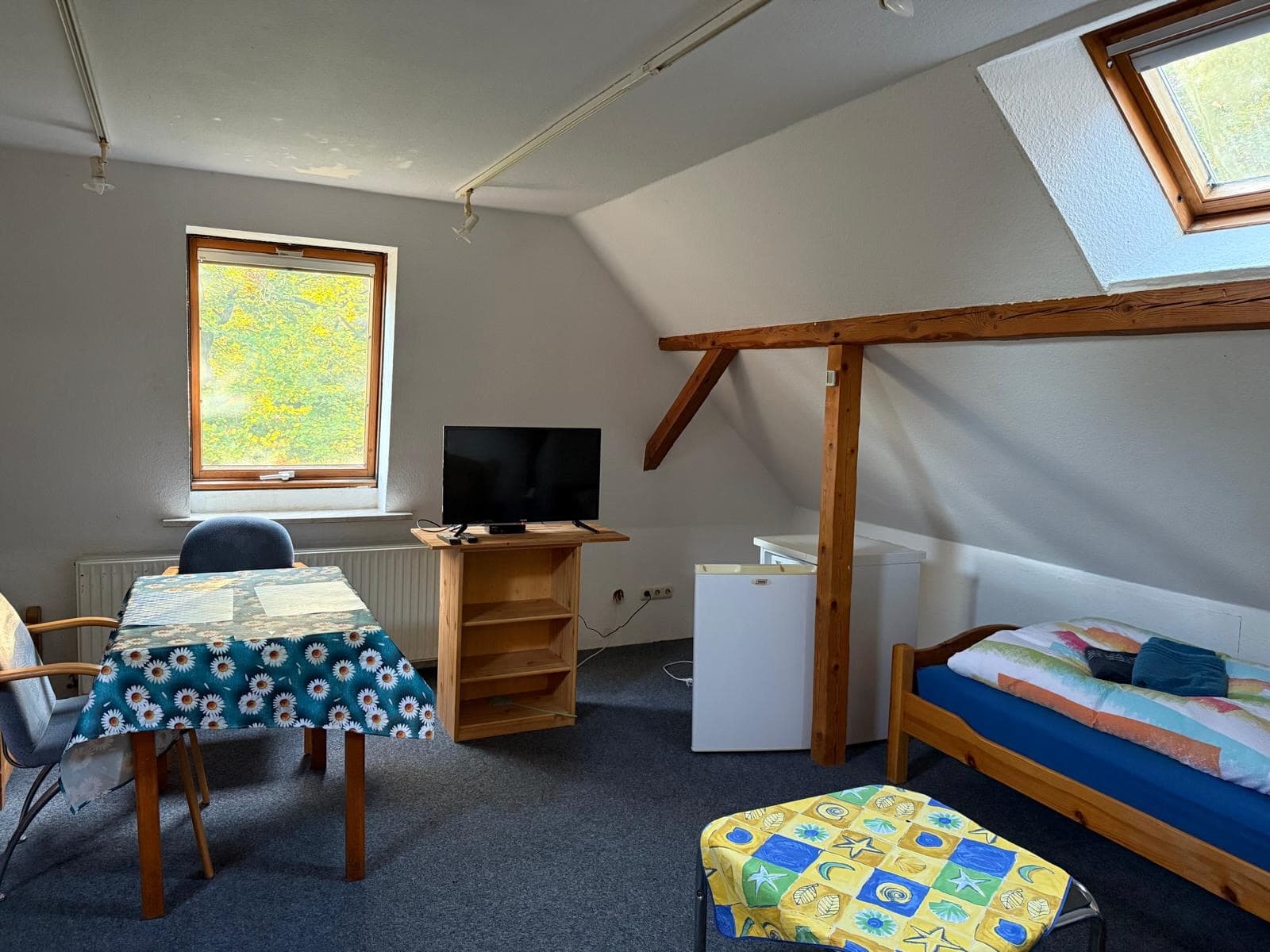 Dachgeschosszimmer mit Bett, Tisch und Fernseher