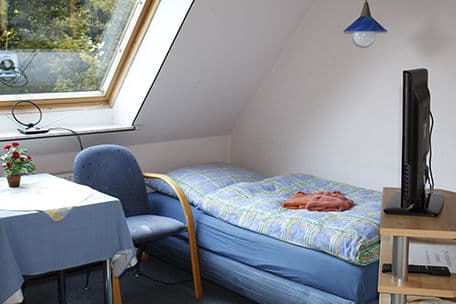 Dachgeschosszimmer mit Bett, Tisch und Fernseher